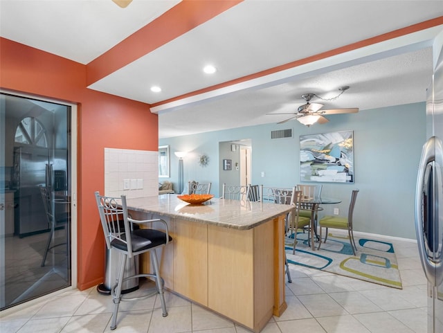 4700 Cove Cir Unit 301, Saint Petersburg, FL 33708 - kitchen featuring ceiling fan, light stone countertops, stainless steel fridge, light tile patterned floors, and a peninsula