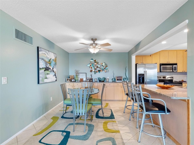 4700 Cove Cir Unit 301, Saint Petersburg, FL 33708 - dining room with light tile patterned floors, ceiling fan, and a textured ceiling