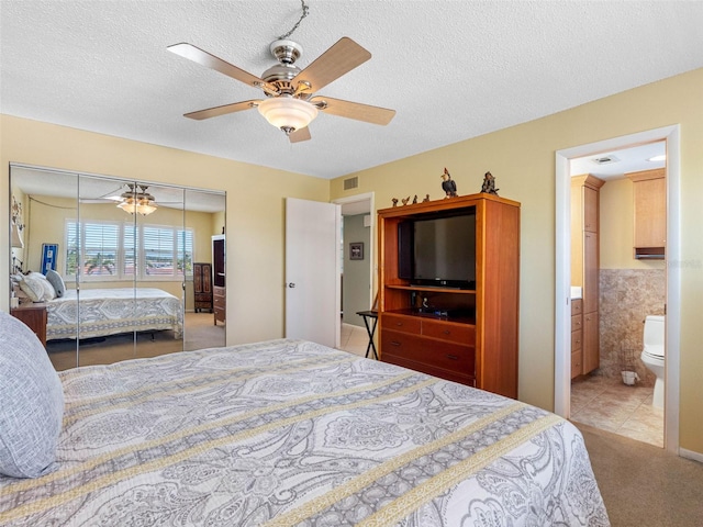 4700 Cove Cir Unit 301, Saint Petersburg, FL 33708 - bedroom with carpet floors, a closet, ceiling fan, ensuite bath, and a textured ceiling