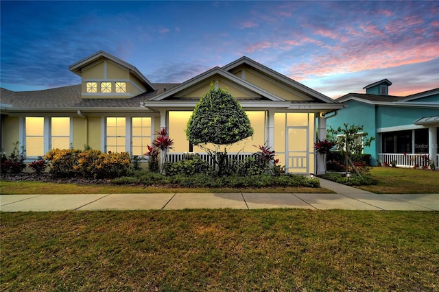view of front of house with a lawn, stucco siding, and roof with shingles