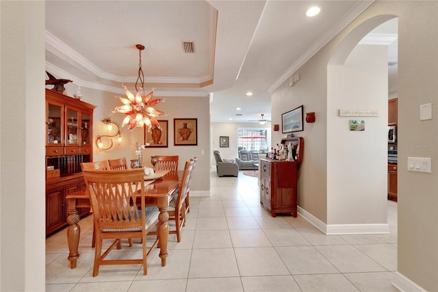dining space featuring ornamental molding, arched walkways, a chandelier, light tile patterned flooring, and baseboards