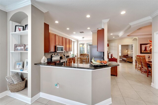 kitchen with appliances with stainless steel finishes, ornamental molding, a peninsula, brown cabinets, and light tile patterned floors