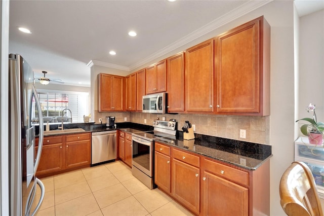 kitchen with appliances with stainless steel finishes, a sink, light tile patterned flooring, ornamental molding, and backsplash