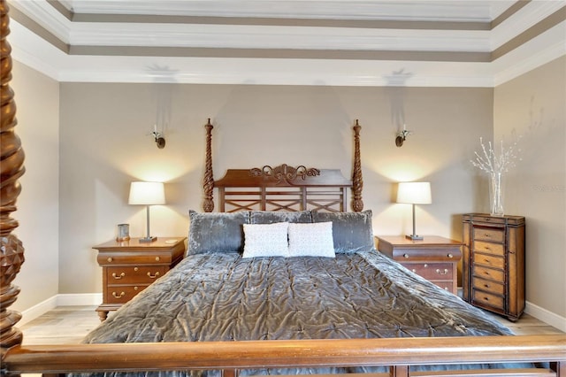 bedroom with wood finished floors, ornamental molding, a tray ceiling, and baseboards