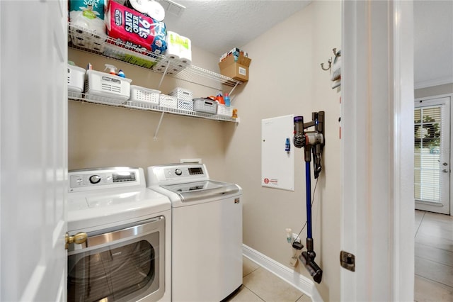 clothes washing area with independent washer and dryer, light tile patterned floors, and baseboards