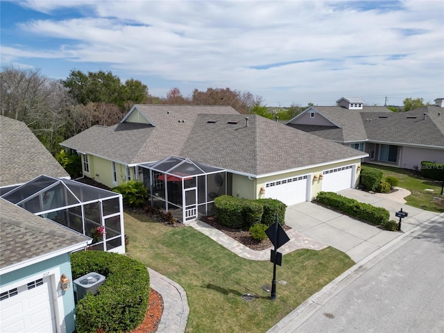 view of front of property with roof with shingles, a garage, concrete driveway, a front lawn, and a lanai