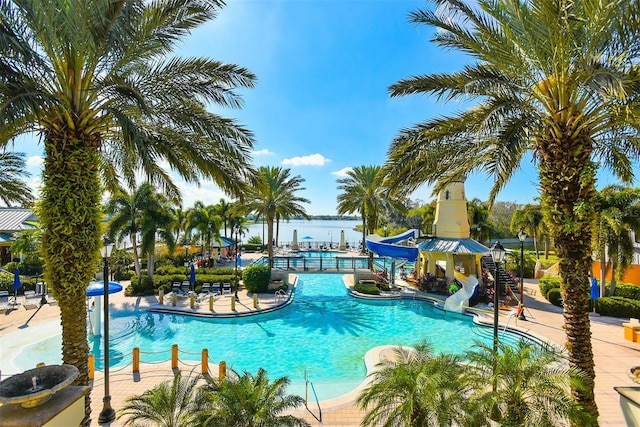 community pool featuring a water slide, a patio, and a water view