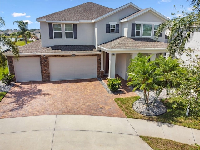 4950 Chase Ct, Saint Cloud, FL 34772 - view of front of home with stucco siding, a shingled roof, decorative driveway, an attached garage, and stone siding
