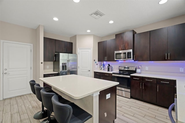 1520 W Fig St, Tampa, FL 33606 - kitchen featuring stainless steel appliances, wood tiled floors, light countertops, a kitchen bar, and a center island