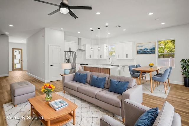 living room with light wood-type flooring, ceiling fan, healthy amount of natural light, baseboards, and recessed lighting
