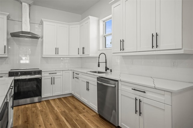 kitchen featuring stainless steel dishwasher, wall chimney exhaust hood, electric range oven, a sink, and white cabinetry