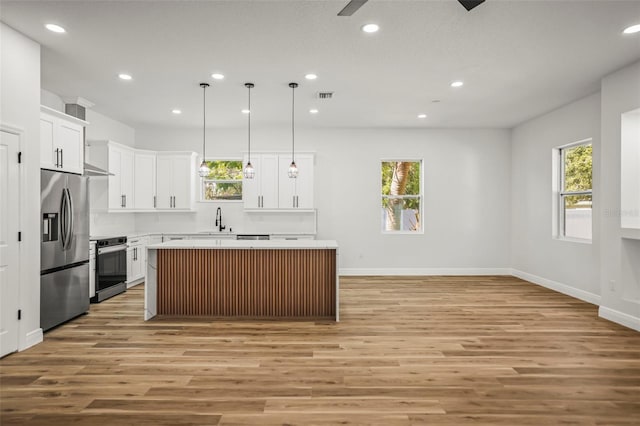 kitchen with stainless steel fridge, electric stove, light wood finished floors, recessed lighting, and a kitchen island
