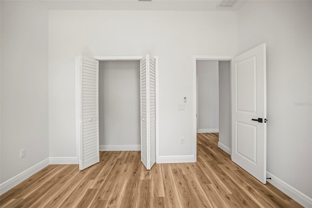 unfurnished bedroom with light wood-type flooring, baseboards, and a closet