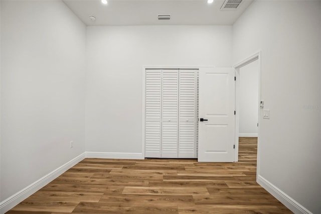 unfurnished bedroom with recessed lighting, baseboards, wood finished floors, and a closet