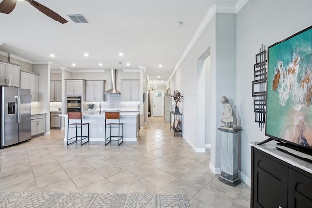 31510 Cabana Rye Ave, San Antonio, FL 33576 - kitchen with appliances with stainless steel finishes, wall chimney exhaust hood, ceiling fan, ornamental molding, and a kitchen bar