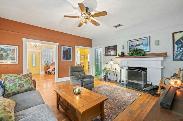 916 E Broad St, Tampa, FL 33604 - living room featuring wood finished floors, ceiling fan, a fireplace with flush hearth, a textured wall, and a chandelier