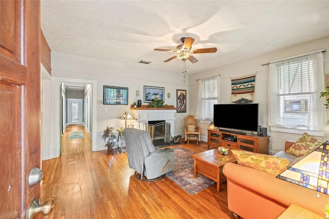 916 E Broad St, Tampa, FL 33604 - living room featuring light wood-style floors, ceiling fan, a glass covered fireplace, and a textured ceiling
