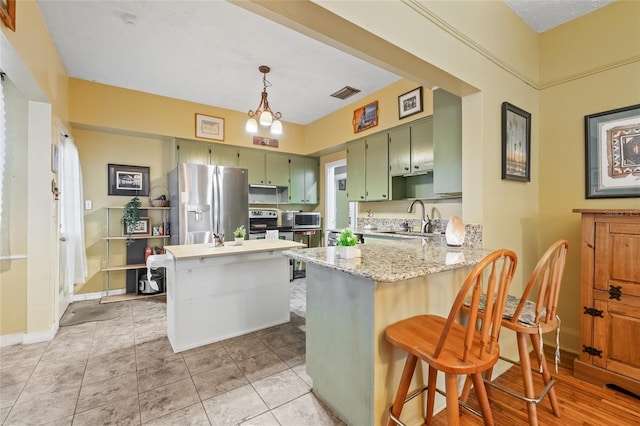 916 E Broad St, Tampa, FL 33604 - kitchen with stainless steel appliances, green cabinetry, a sink, a peninsula, and light stone countertops