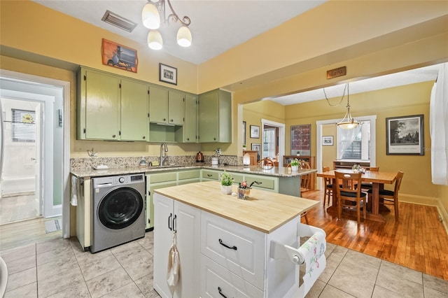 916 E Broad St, Tampa, FL 33604 - kitchen featuring washer / clothes dryer, green cabinets, light tile patterned floors, a sink, and decorative light fixtures