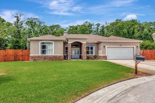 single story home with stucco siding, stone siding, a garage, and driveway