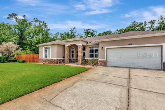 ranch-style home featuring stone siding, stucco siding, concrete driveway, and an attached garage