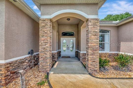 view of exterior entry featuring stucco siding and stone siding