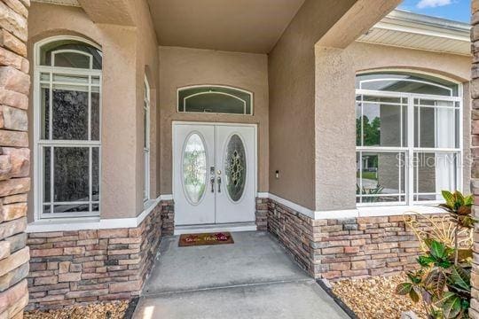 doorway to property featuring stucco siding and stone siding