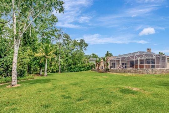view of grassy yard with a lanai