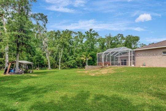 view of grassy yard with a gazebo and glass enclosure