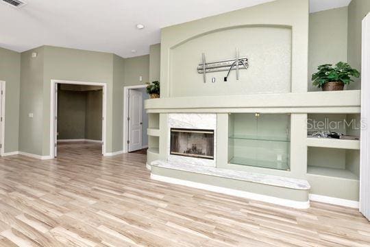 unfurnished living room featuring wood finished floors, baseboards, and a premium fireplace