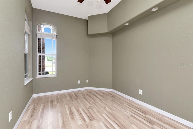 spare room with ceiling fan, light wood-style floors, and baseboards