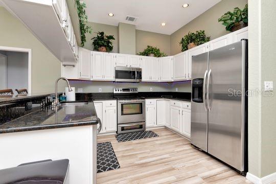 kitchen featuring appliances with stainless steel finishes, a sink, light wood-type flooring, white cabinetry, and recessed lighting