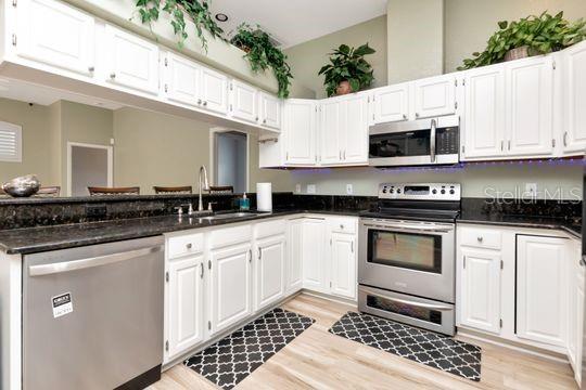 kitchen featuring appliances with stainless steel finishes, a sink, white cabinets, and light wood finished floors