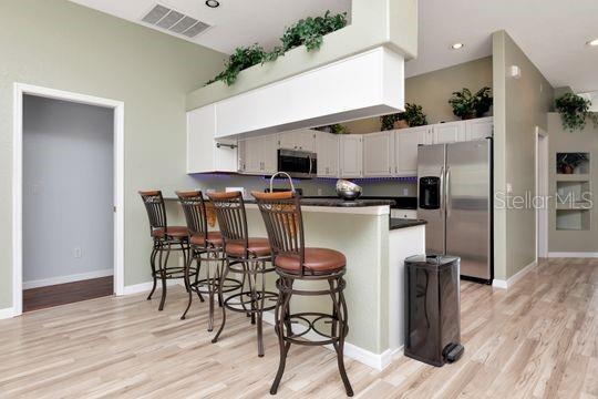 kitchen with stainless steel appliances, a peninsula, light wood finished floors, dark countertops, and recessed lighting