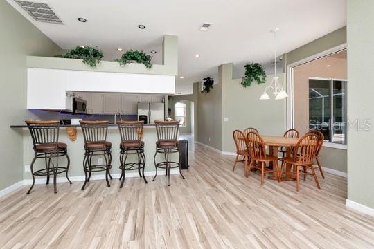 kitchen with appliances with stainless steel finishes, light wood-style flooring, a breakfast bar area, and recessed lighting