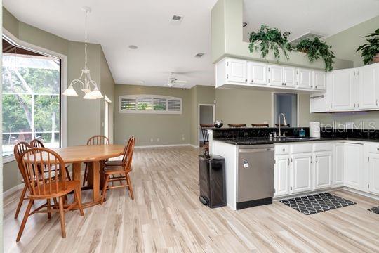 kitchen featuring a sink, dishwasher, light wood-style flooring, baseboards, and white cabinets