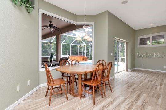 dining room with wood finished floors, a sunroom, baseboards, and a ceiling fan