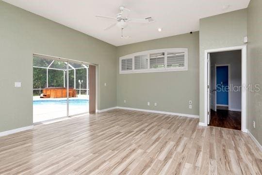 unfurnished room with ceiling fan, light wood finished floors, baseboards, and a sunroom