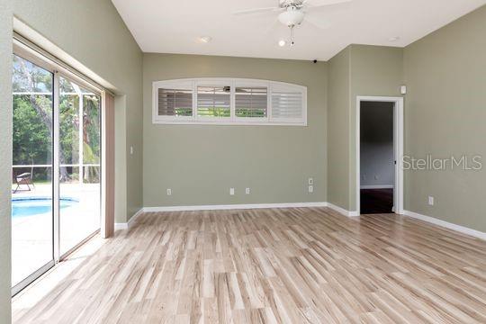 unfurnished room featuring light wood-style floors, plenty of natural light, a ceiling fan, and baseboards