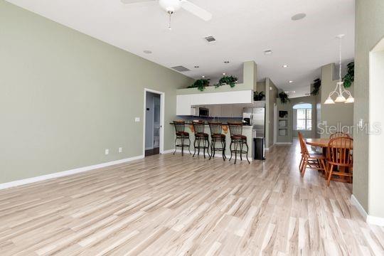 kitchen featuring light wood-type flooring, a ceiling fan, a kitchen bar, white cabinetry, and baseboards