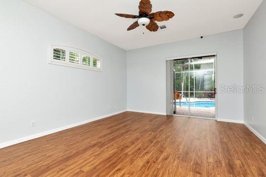 spare room with wood finished floors, a ceiling fan, and baseboards
