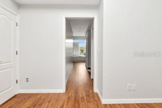 corridor featuring wood finished floors and baseboards