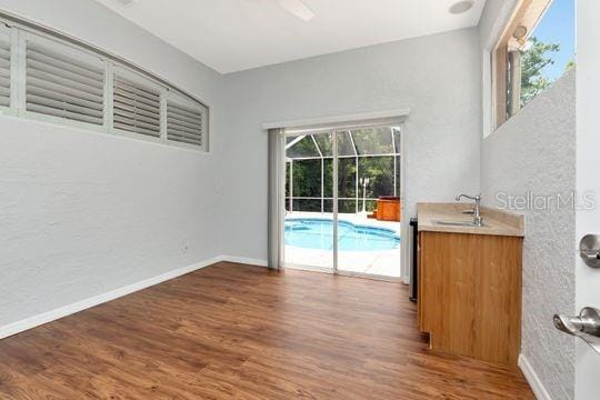 unfurnished room with wood finished floors, a sink, and baseboards