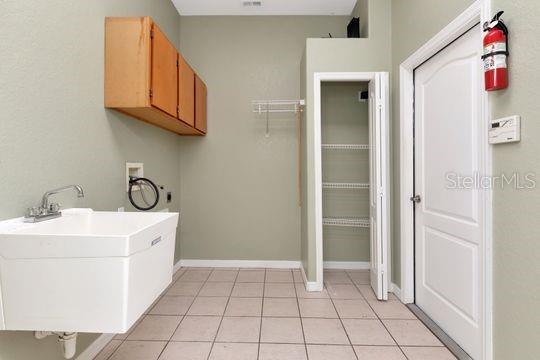 laundry area with washer hookup, cabinet space, hookup for an electric dryer, light tile patterned floors, and baseboards