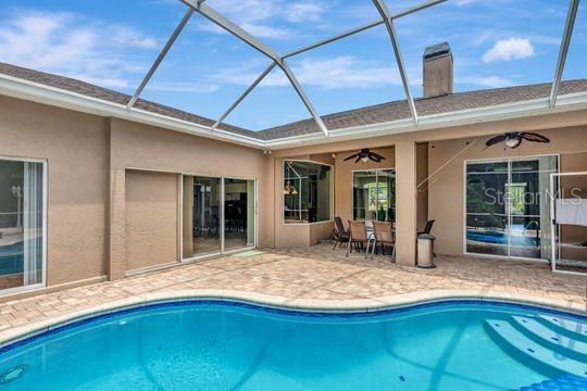 outdoor pool featuring a ceiling fan, a patio, a lanai, and outdoor dining area