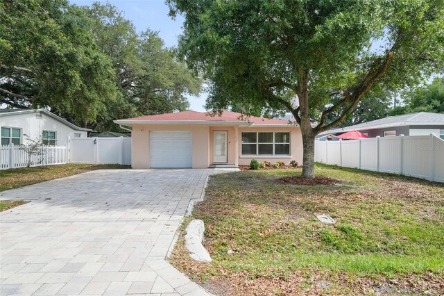 ranch-style house featuring decorative driveway, a garage, stucco siding, and fence