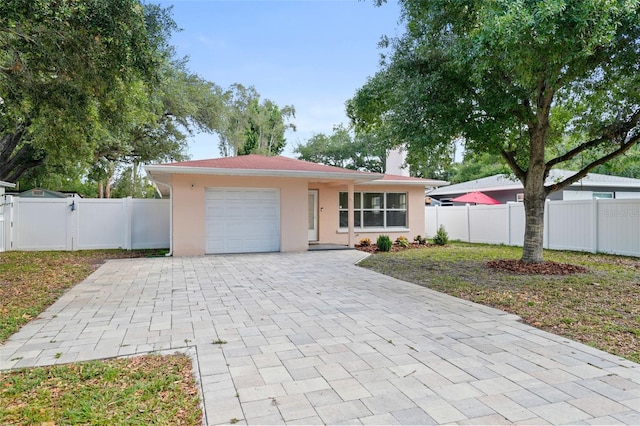 ranch-style home with a garage, decorative driveway, stucco siding, a fenced backyard, and a gate