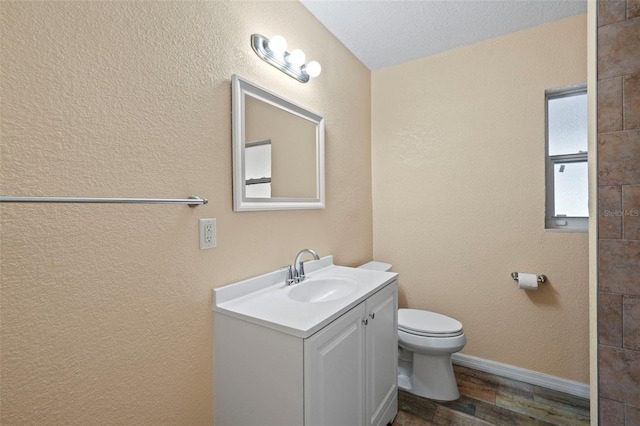 bathroom featuring wood finished floors, toilet, vanity, and baseboards