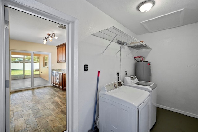 clothes washing area featuring washer and dryer, water heater, wood finished floors, attic access, and baseboards