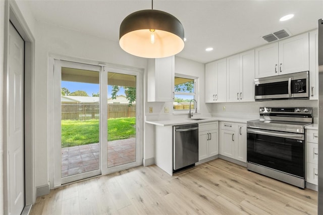 7400 Belvedere Ter, New Port Richey, FL 34655 - kitchen featuring appliances with stainless steel finishes, a sink, light countertops, white cabinetry, and recessed lighting